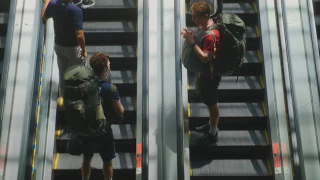 Young travellers with backpacks on an airport escalator